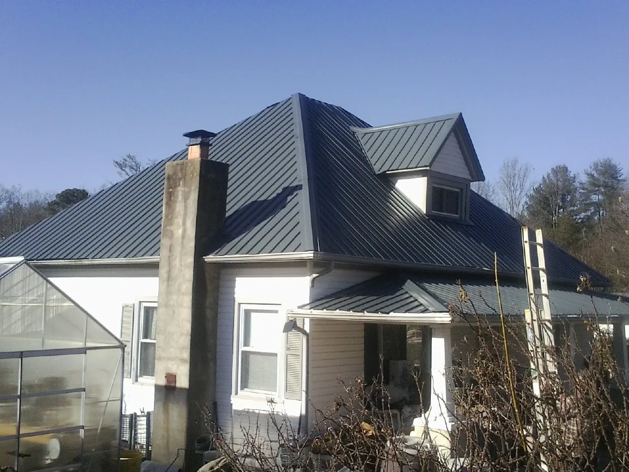 Dark blue standing seam metal roof on a white farmhouse with dormer — Slate & Tile Roof Repair by Roofing Brothers in Cottontown