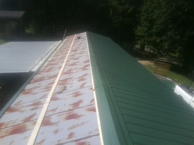 Old rusted panels beside newly installed green metal roofing — Wind Damage Roof Repair by Roofing Brothers in Cottontown
