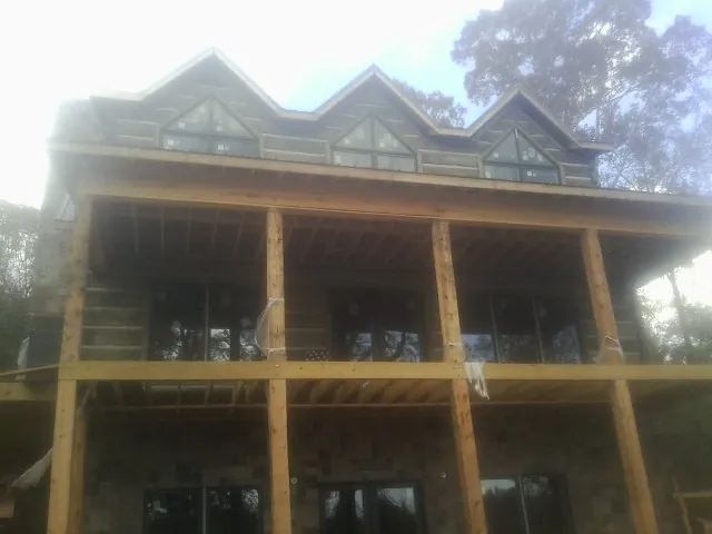 Dormers and porch framing on a large log home under construction — Roof Coating work by our crew in Cottontown