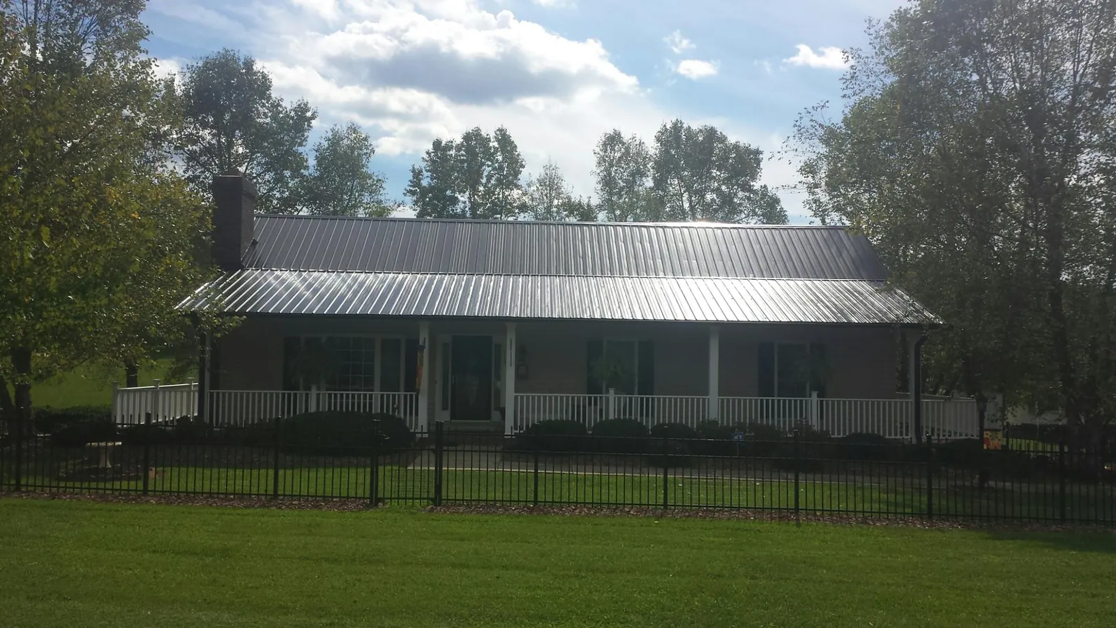 Gray metal roof on a brick ranch with a full width front porch — Gutter Guard Installation work by our crew in Cottontown