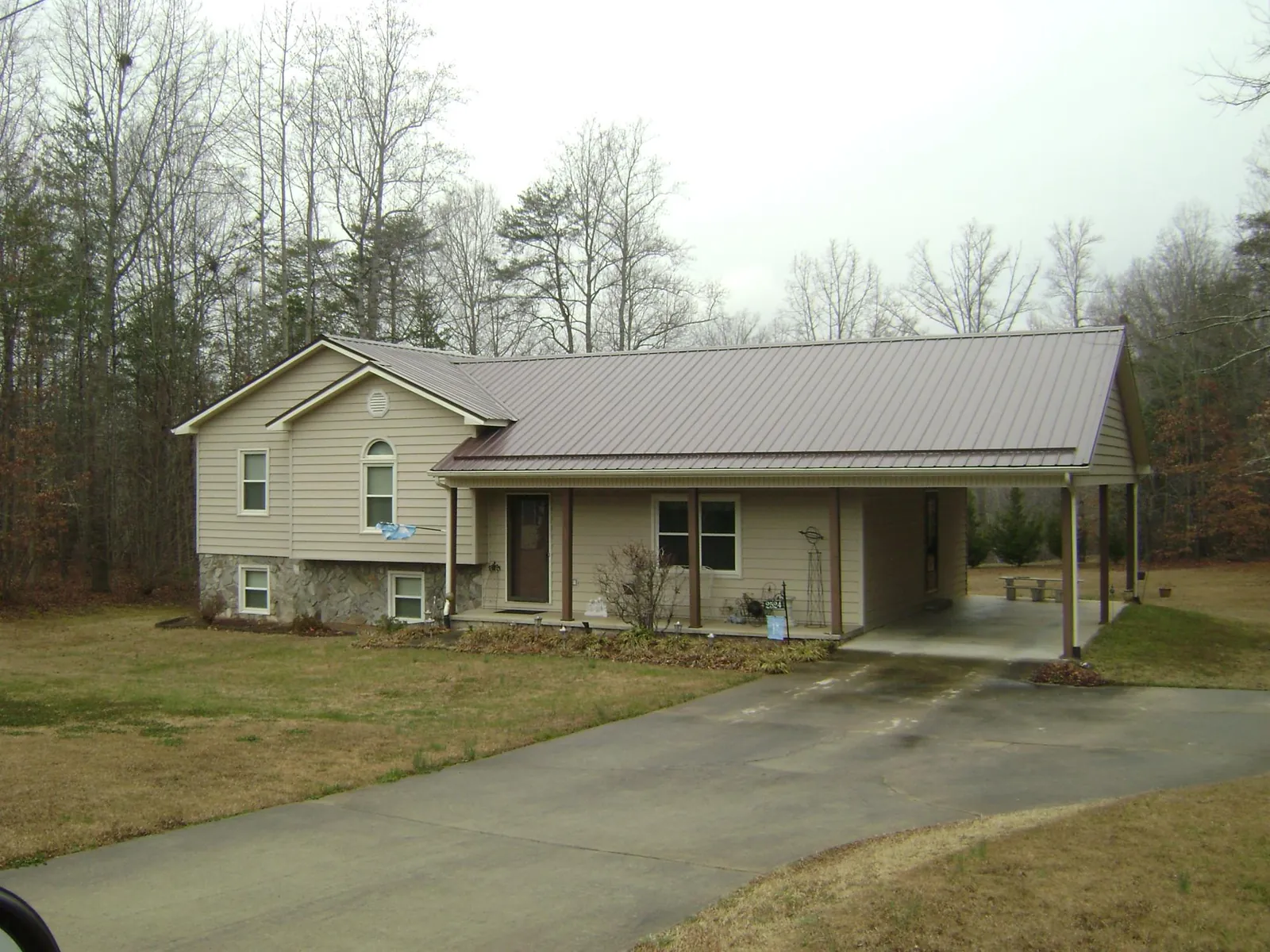 Brown metal roof on a tan split level home with an attached carport in Cottontown