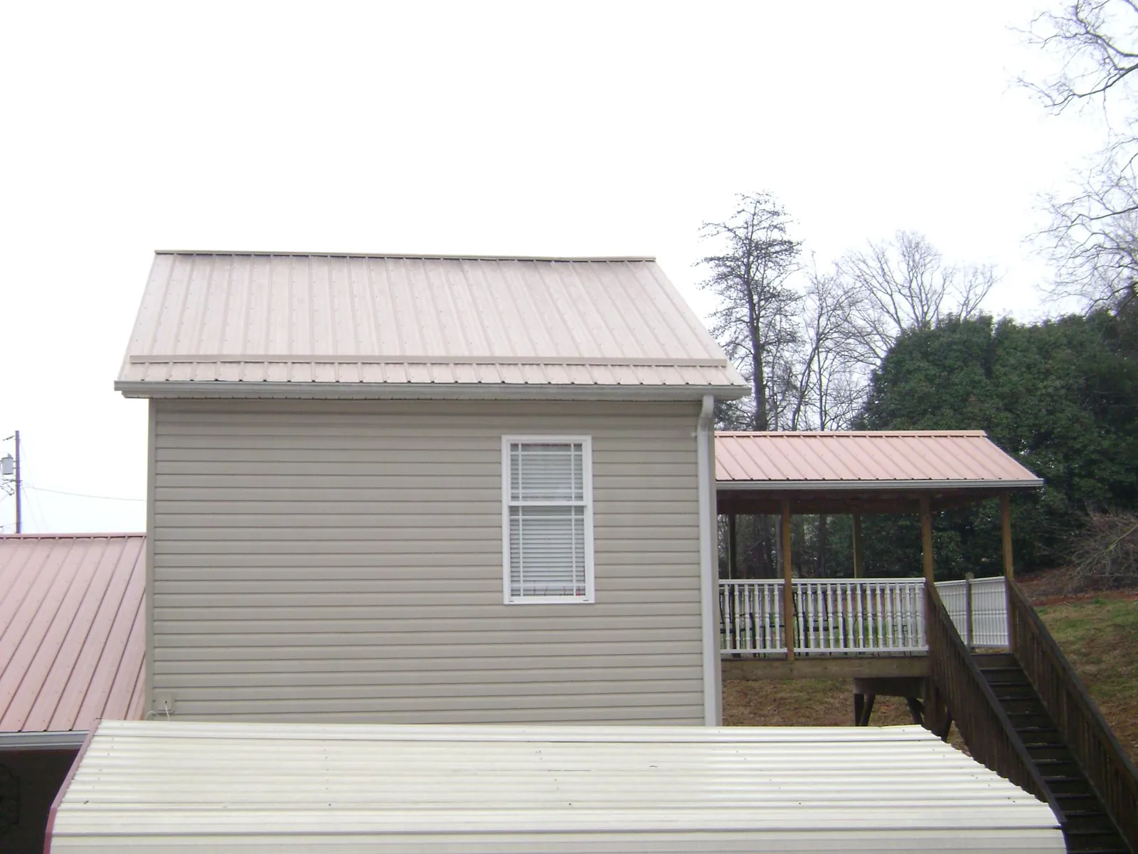 Tan metal roofs on a two story addition and attached porch, from a Roof Replacement job in Cottontown